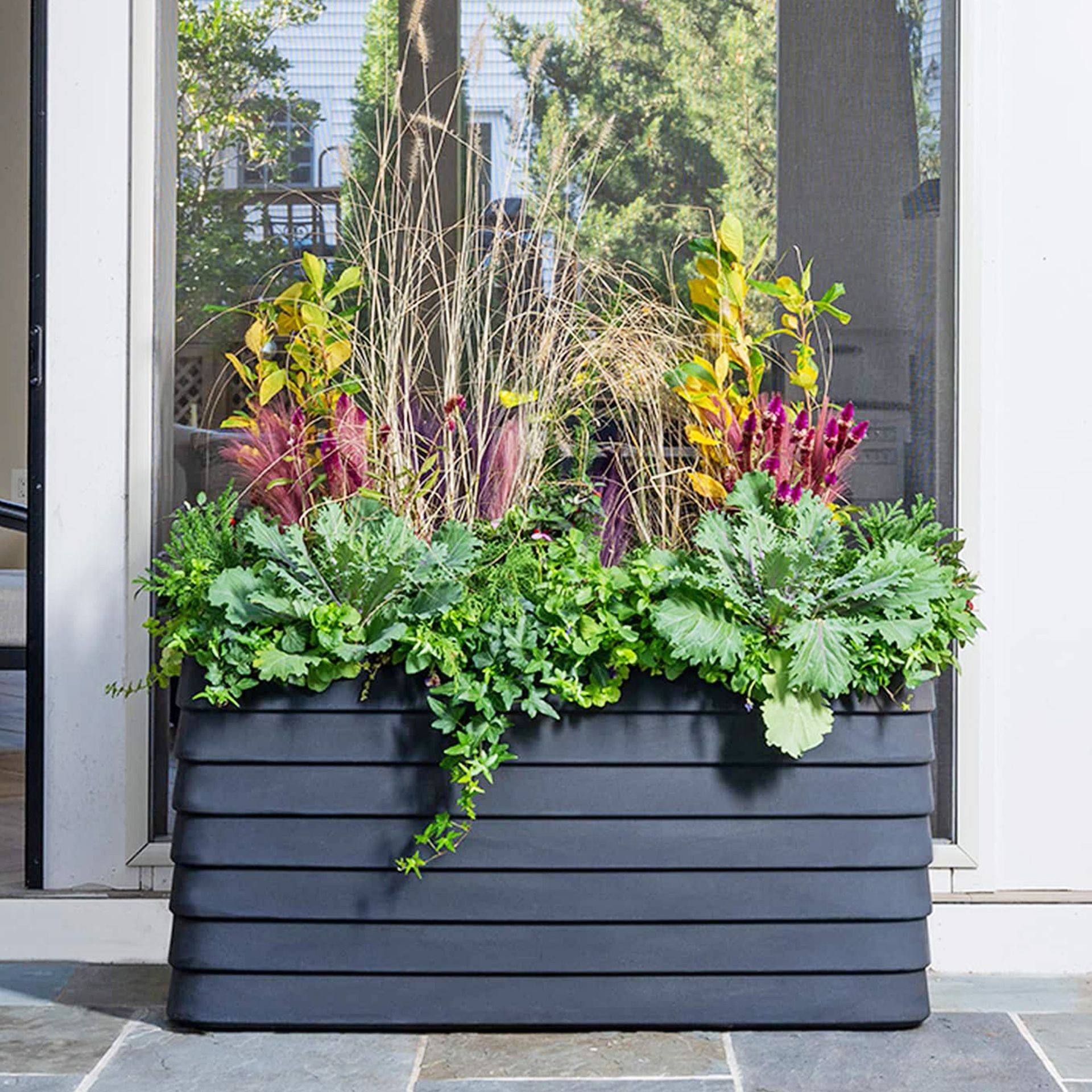 A modern self-watering planter box with slatted design, ideal for patios.