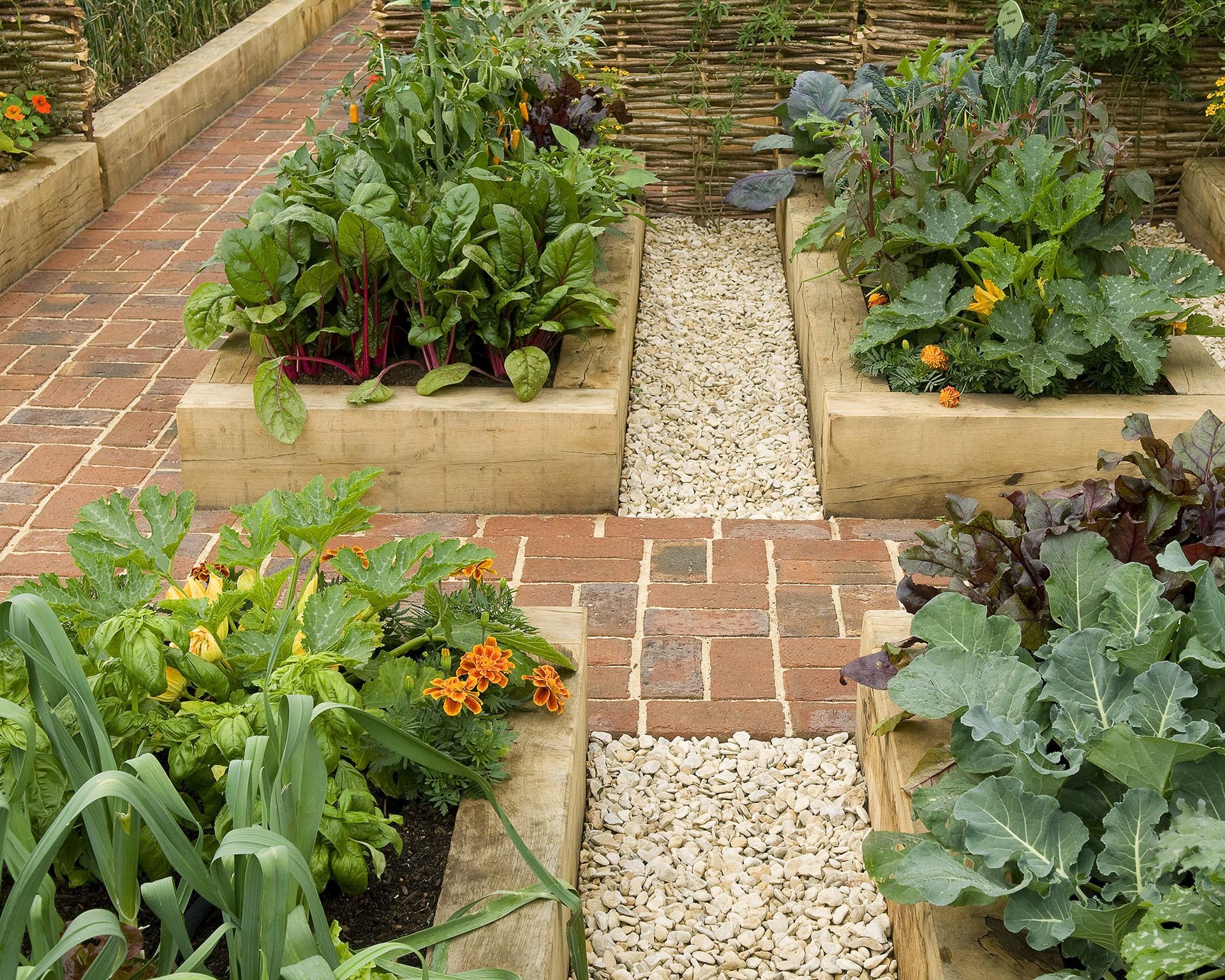 Attractive pathways made of brick and gravel wind through a vegetable garden area featuring raised beds, showing good design and access