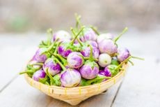 Basket filled with small, dark purple Indian eggplants