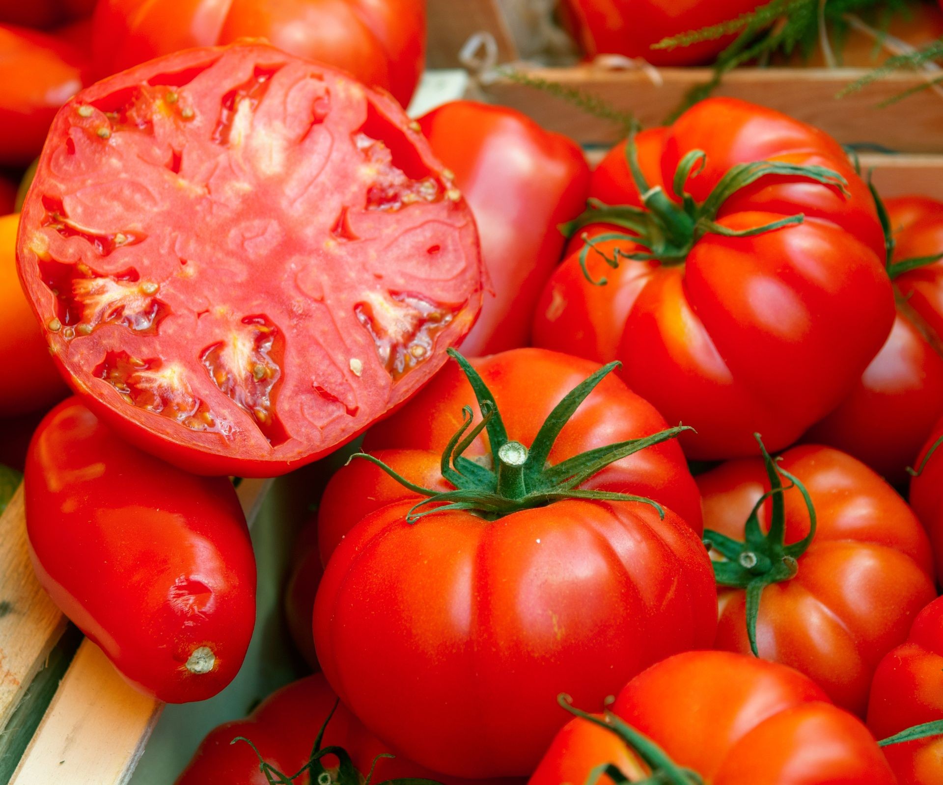 Close-up of large, ripe red beefsteak tomatoes, one sliced to show the juicy interior, perfect for sandwiches.