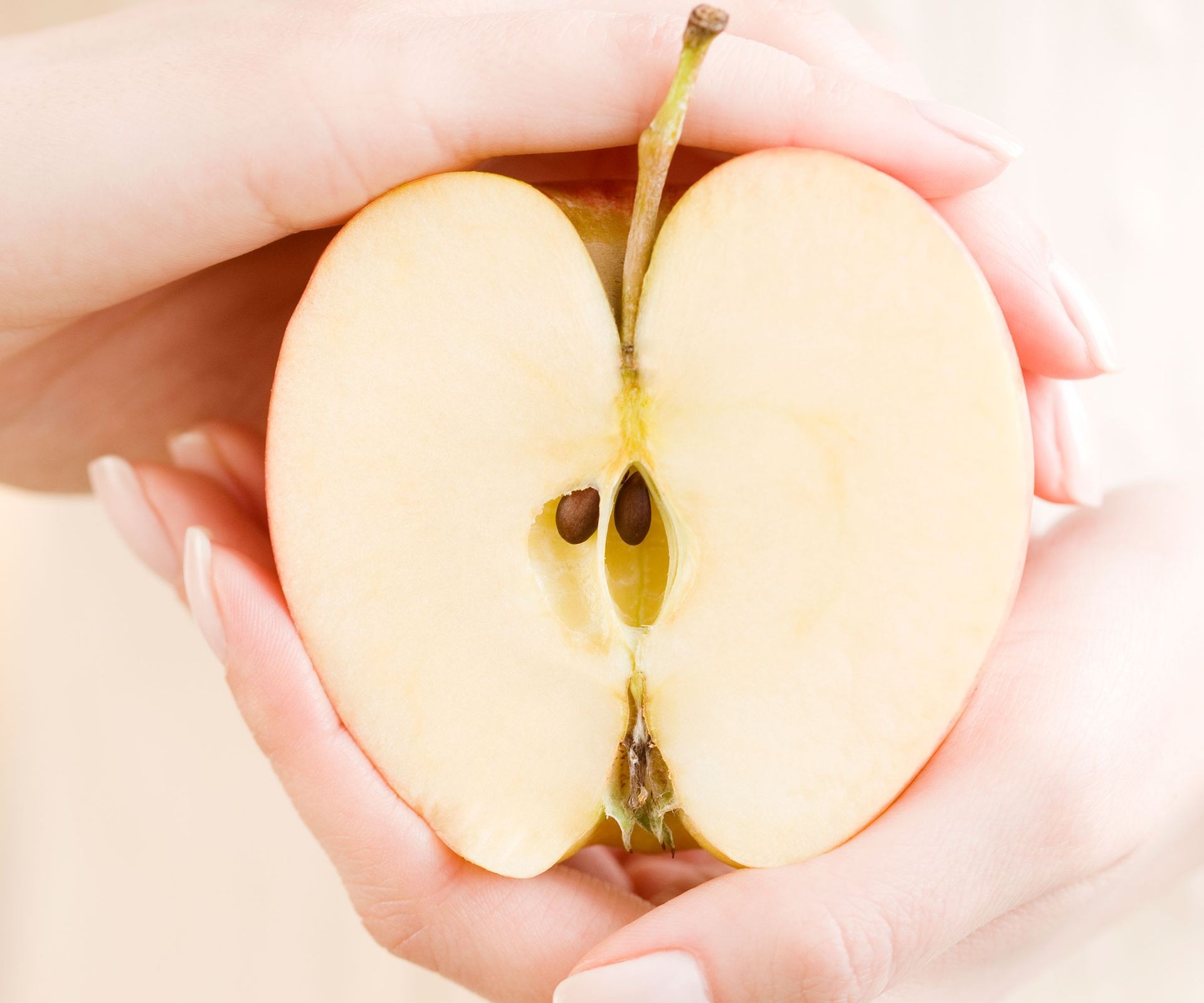 Close-up view of a red apple sliced open, revealing the central core and dark brown apple seeds ready for planting