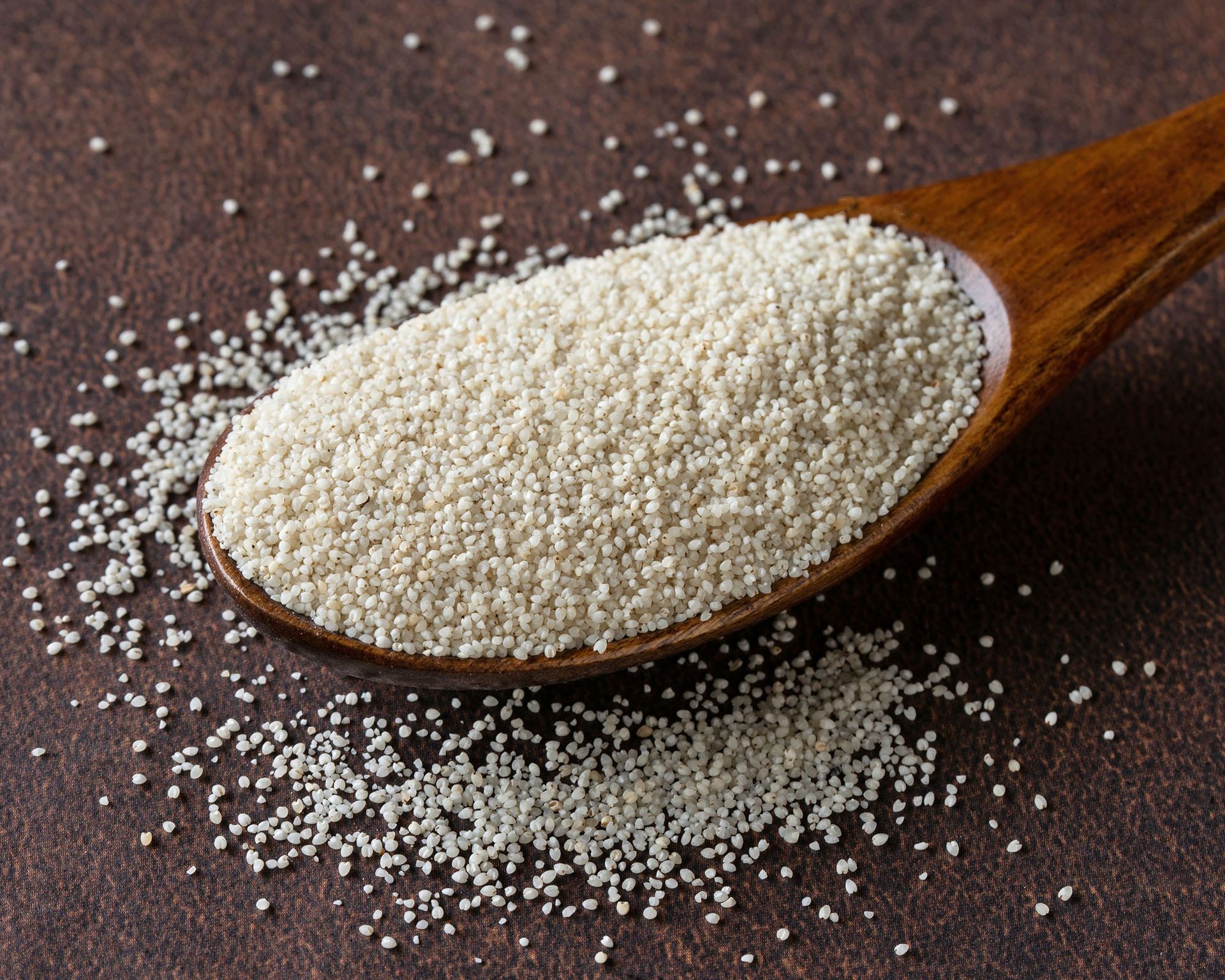 Close-up view of tiny fonio grains held in a wooden spoon