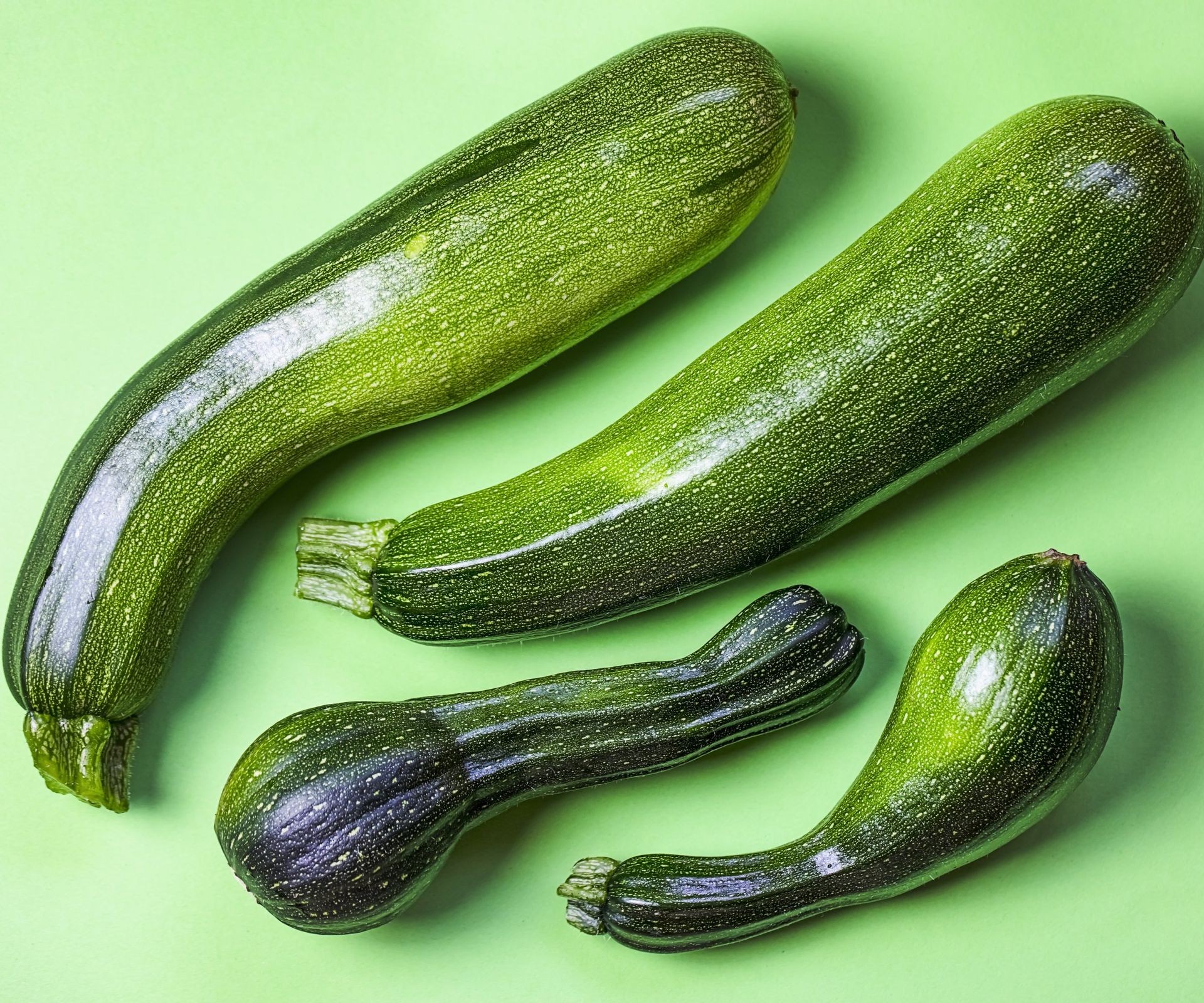 Four green zucchini side by side