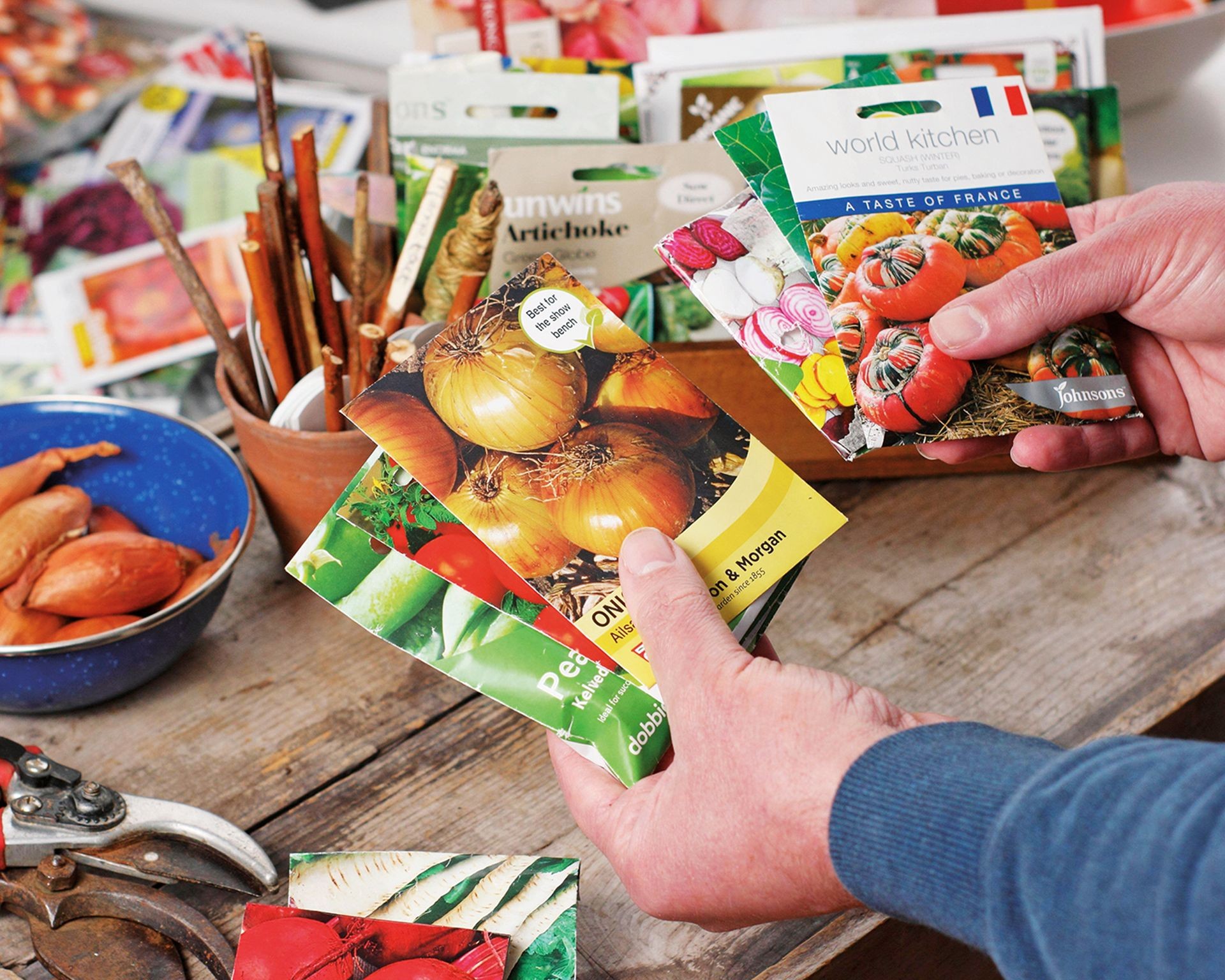 Gardener holding packets of vegetable seeds, planning their garden planting
