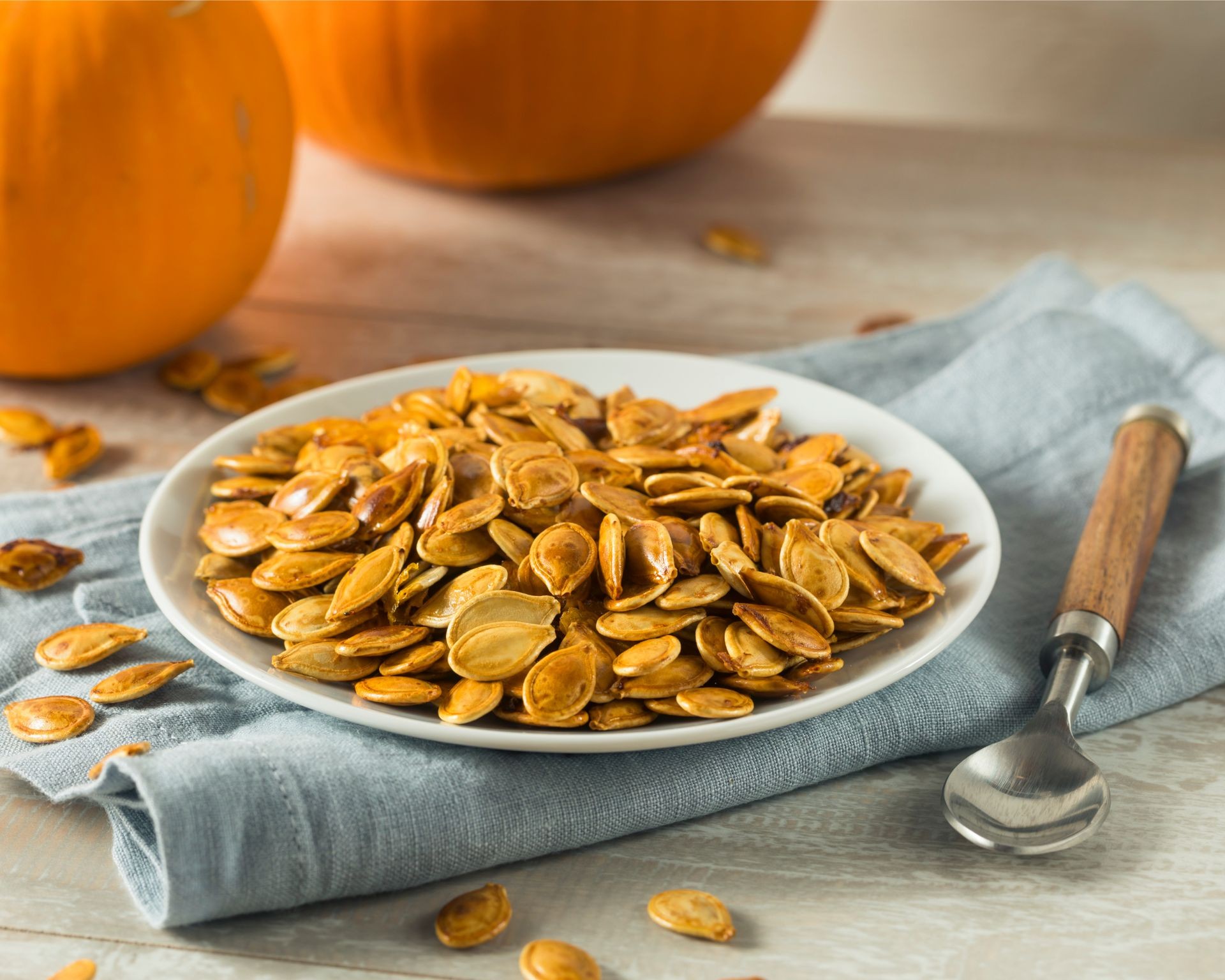 Roasted pumpkin seeds on a plate with a spoon ready to be enjoyed