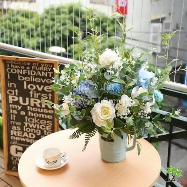 Rose arrangement in a tall, rustic-looking vase with other wildflowers
