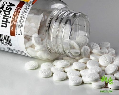 Several white aspirin tablets next to a glass of water, illustrating the use of aspirin to help peach blossoms bloom faster