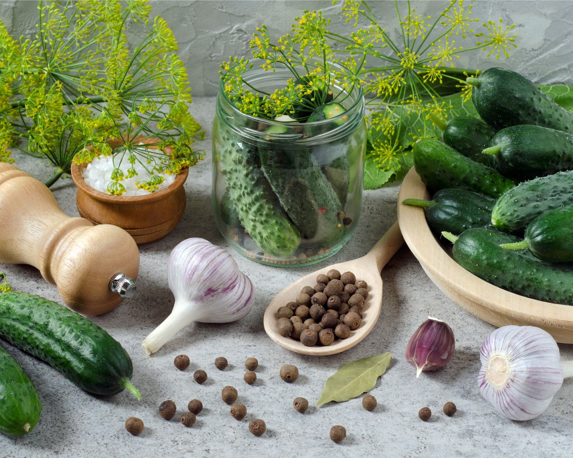 Various fresh vegetables like cucumbers, peppers, and herbs arranged on a counter for pickling preparation