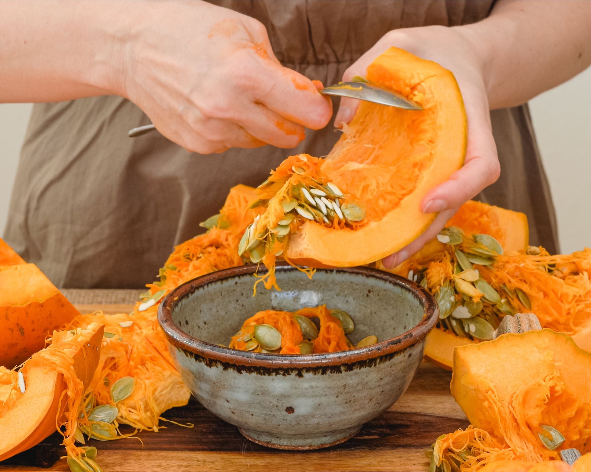 Woman scooping out pumpkin seeds from a halved pumpkin